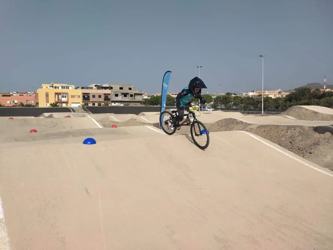 Rider de BMX sobre los rodillos de una pista con superficie mineral