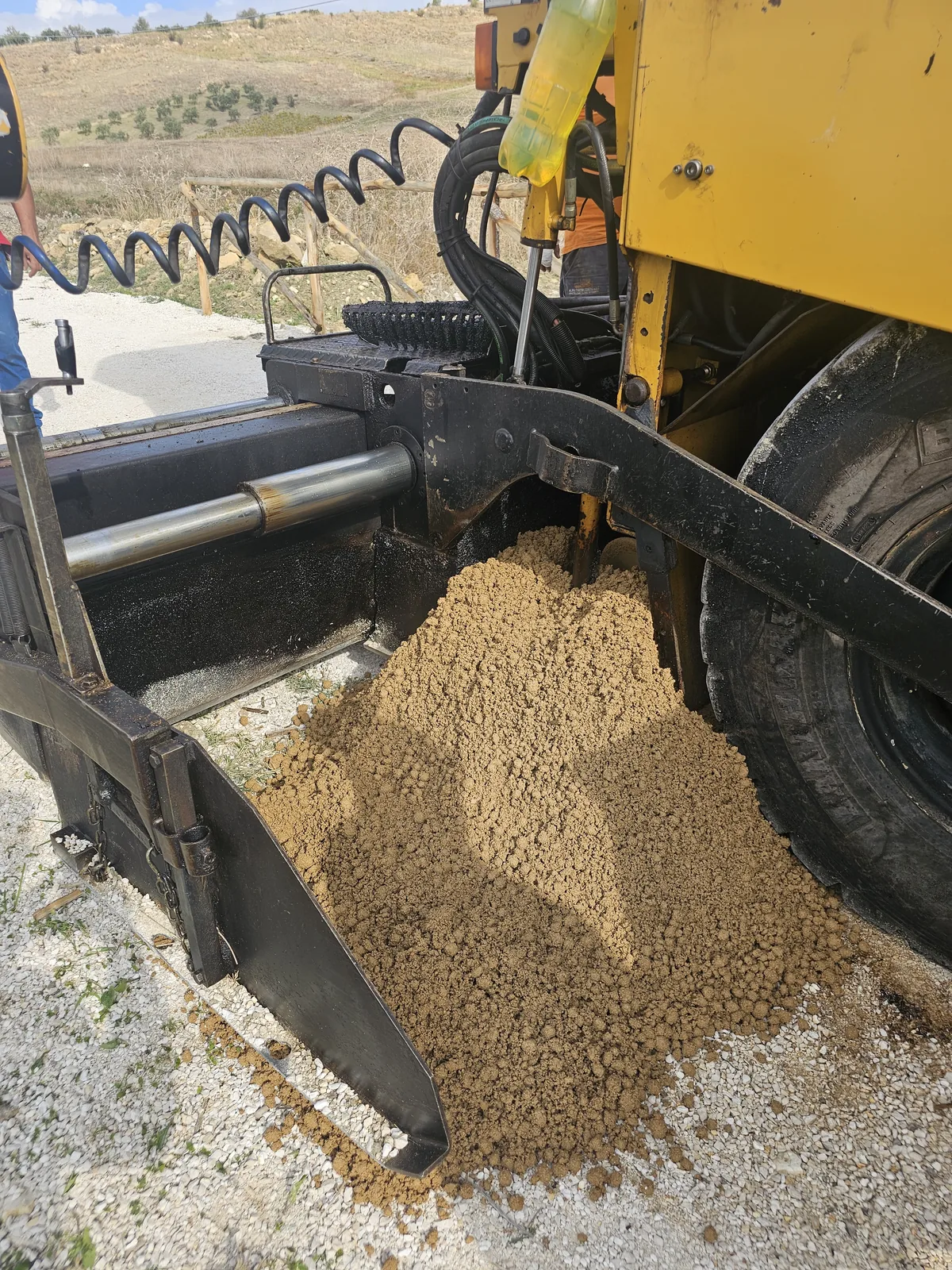 Material mineral junto a la maquinaria de extendido durante la ejecución de un pavimento