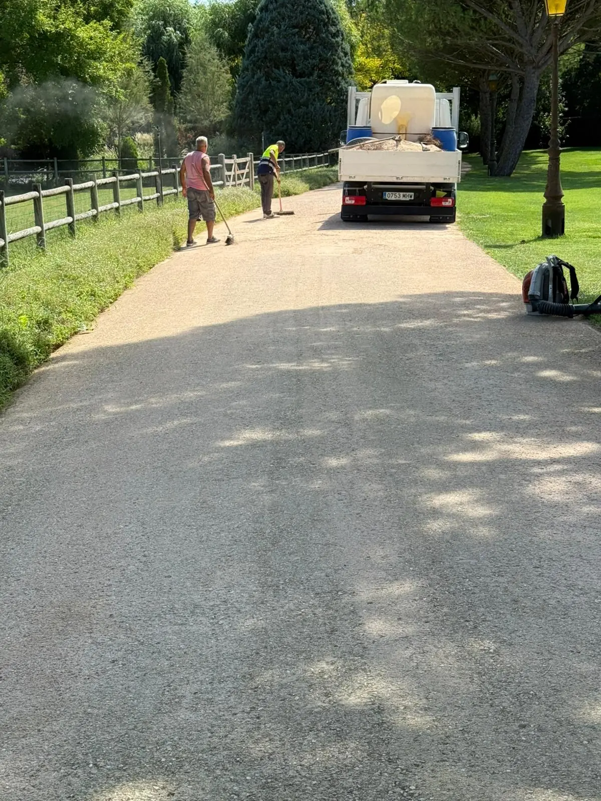 Dos operarios preparando la superficie de un camino de tierra antes del tratamiento de protección superficial